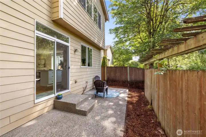 Back patio with a fully fenced yard — a private outdoor space backed by mature trees
