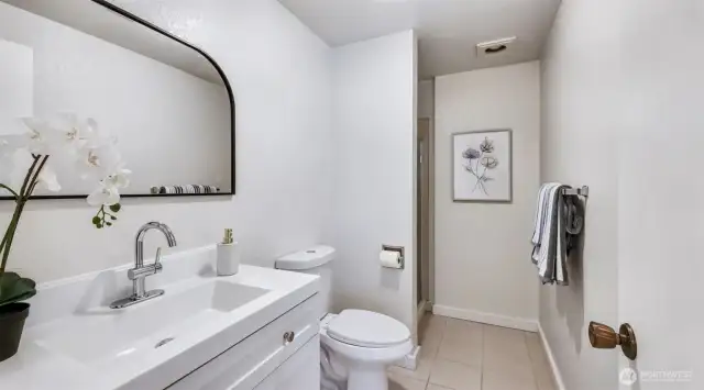 Stylish 3/4 bathroom featuring a modern design, complemented by a beautiful vanity and a polished mirror complete the lower level of this home.