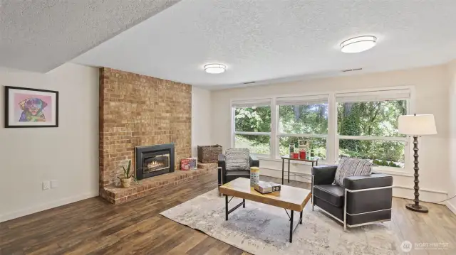 The lower level features a charming brick fireplace and abundant natural light from the wall of windows, offering an open, inviting space ready to be personalized with your own furniture and style.