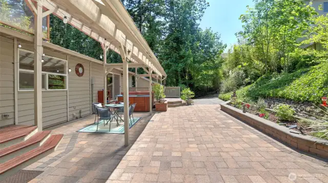 A beautiful paver patio with custom-made raised flower beds seamlessly extends your living to this tranquil and mature yard, connecting different areas with ease and providing convenient access.