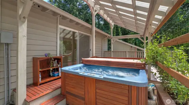 Covered porch area features a relaxing hot tub plus extra space and storage to keep your outdoor essentials organized and close by.