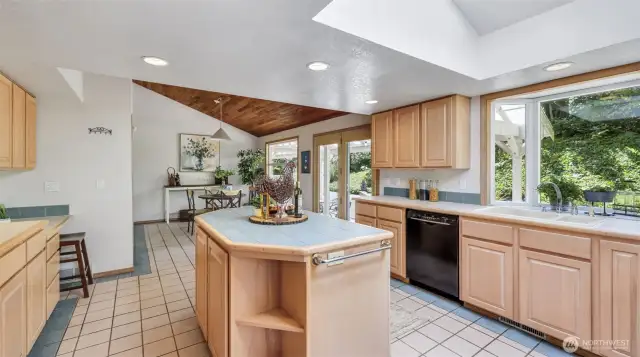 Enter to a charmingly designed kitchen boasting a central island, classic wooden cabinetry, and an elegant bay window that floods the space with light.