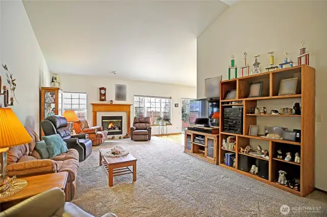Large living room featuring vaulted ceilings, large windows, gas fireplace perfect for relaxing or entertaining.