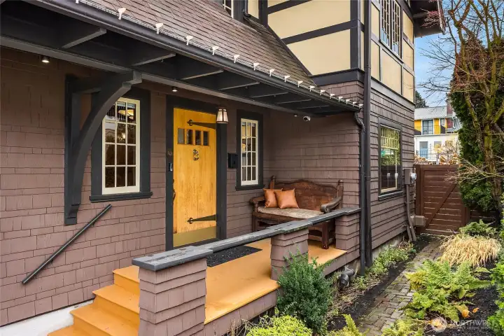 The charming covered entry is so welcoming with it's wood soffits and large wooden porch. Large strap hinges on the front door and the shingled siding is impeccable.