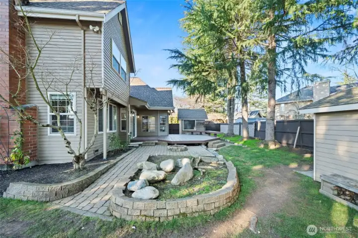 Side yard and patio area with retaining wall landscaping and deck access.