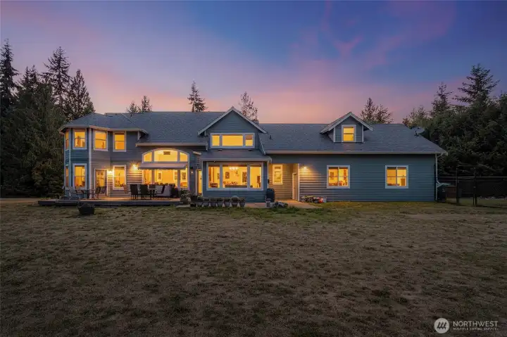 Twilight view of the back exterior with expansive deck.
