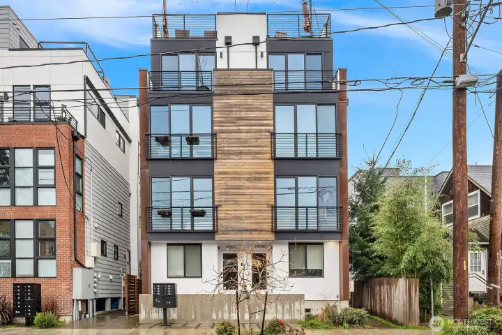 Sleek and contemporary exterior with warm brick accents, abundant glass, and a private turf yard, showcasing the home's modern urban aesthetic in one of Seattle's most vibrant neighborhoods.
