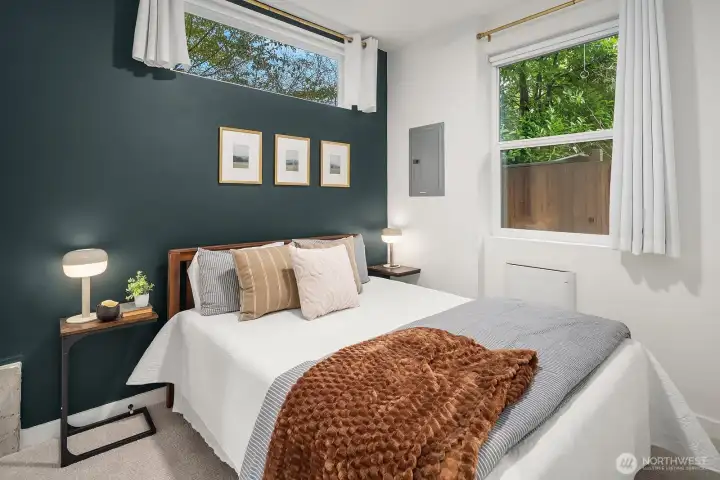 Stylish and intimate primary bedroom featuring a bold accent wall, lush window views, and a warm, curated aesthetic that makes this full-floor suite a true urban retreat.