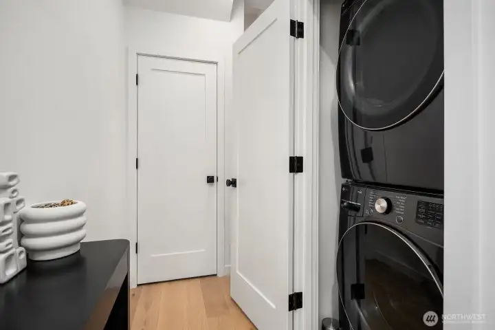 Conveniently located laundry closet with a full-size stacked washer and dryer, keeping everyday essentials neatly tucked away in this efficiently designed urban home.