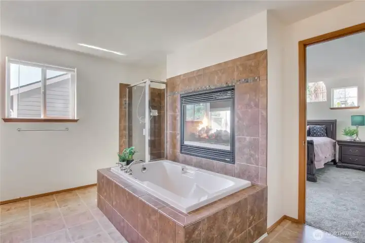 Luxury primary suite bath has romantic jetted tub next to the gas fireplace