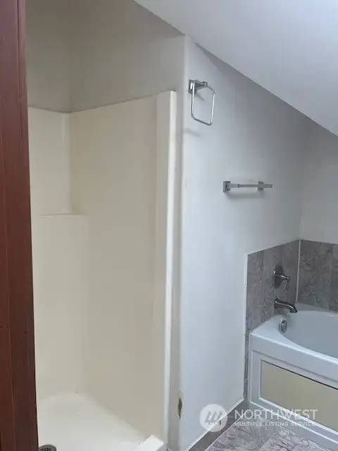 The bathtub is separate from the shower area.