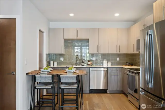 Gourmet kitchen with tile backsplash, quartz counters, stainless steel appliances, induction cooktop, and walk-in pantry.