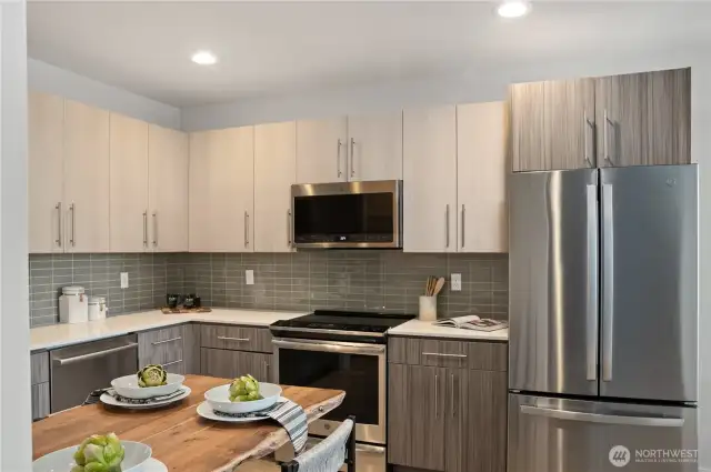 Gourmet kitchen with tile backsplash, quartz counters, stainless steel appliances, induction cooktop, and walk-in pantry.