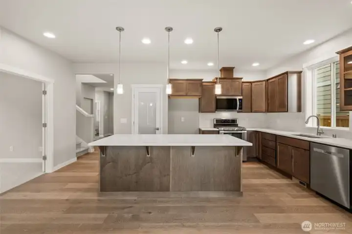 Kitchen features Cocoa-stained Maple Cabinets and Quartz countertops and a large pantry with frosted glass door.