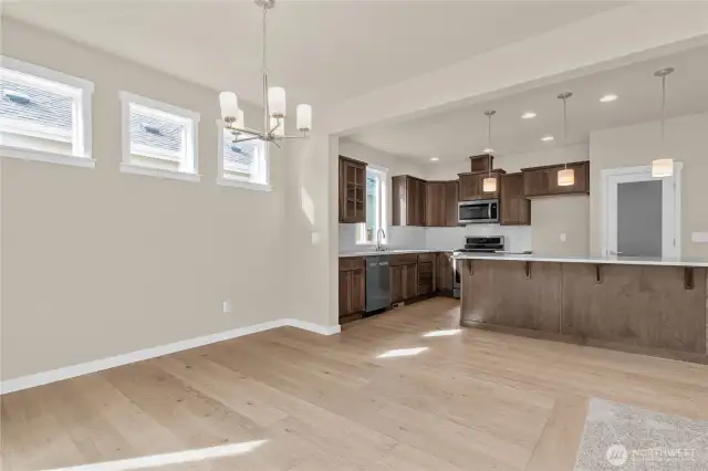 Dining area with high set transom windows for natural light features hardwood flooring.