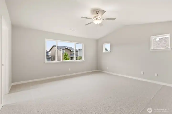 Large primary bedroom featuring a standard ceiling fan and soft carpet for comfort.