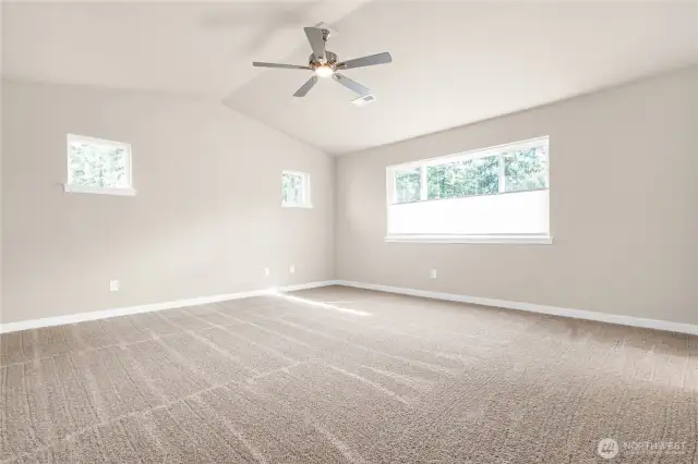 Large primary bedroom featuring a standard ceiling fan and soft carpet for comfort.