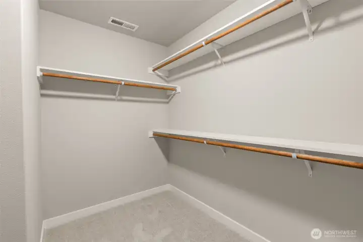 Primary closet is walk-in with extra solid storage shelves above the hanging rods.