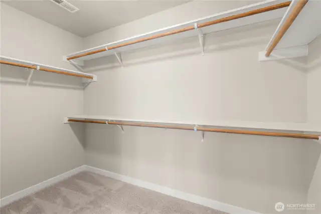 Primary closet is walk-in with extra solid storage shelves above the hanging rods.