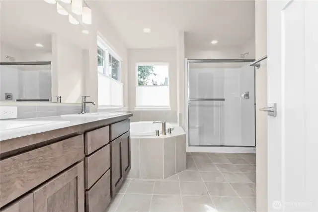 Primary bath is stunning with a double vanity, undermount sinks and backsplash.  and a large soaking tub with tile surround plus tile flooring.