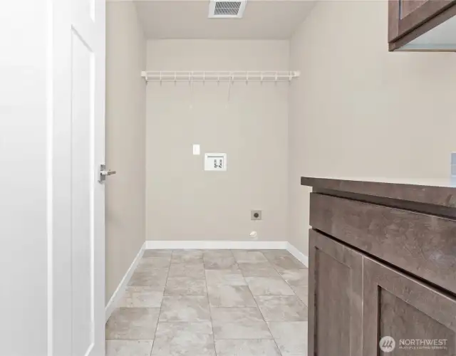 Separate laundry room with a counter, storage cabinets and a storage shelf above appliances.