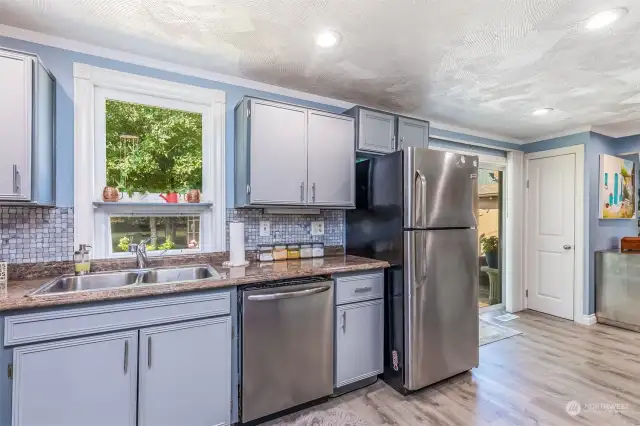 The updated kitchen is light and bright,  freshly painted, and bears easy flow to either  the living area, the dining room, or the  incredible outdoor entertaining space.