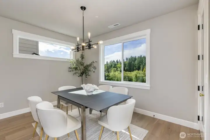 Elegant dining room features a chandelier and tree-top view.