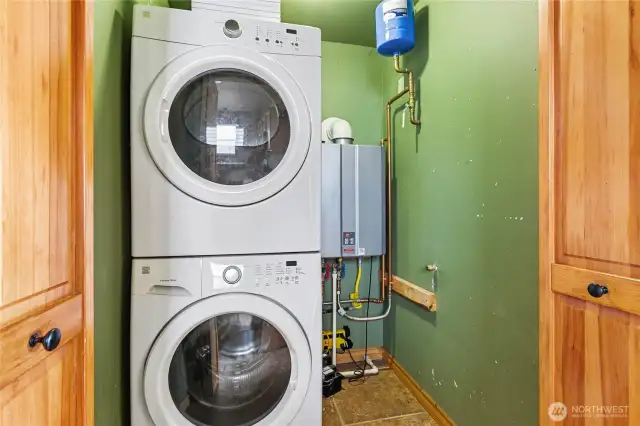 Stacked washer and dryer with a tankless water heater tucked neatly behind closet doors.