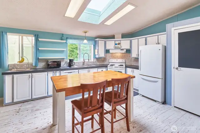 Open plan kitchen with newer counters, faucets and lighting.