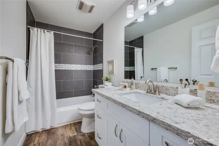 This full bath is located in the hallway of the upper level. It has a lovely custom tile surround.