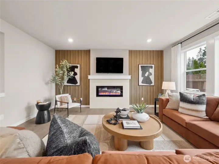 Open concept family room with cozy fireplace and loads of windows. Photo is representational. Actual home is under construction and finishes and colors will vary. See site agent for details.