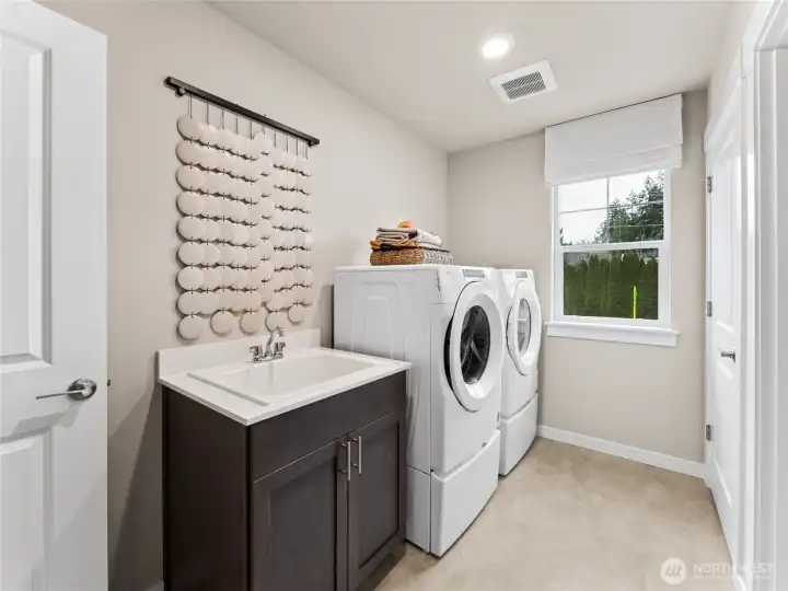 Utility room with sink, and an additional dor leading into primary closet. Photo is representational. Actual home is under construction and finishes and colors will vary. See site agent for details.
