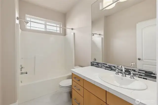 Second full bathroom situated between bedrooms 2 and 3 down a private hallway; linen cabinet as well.