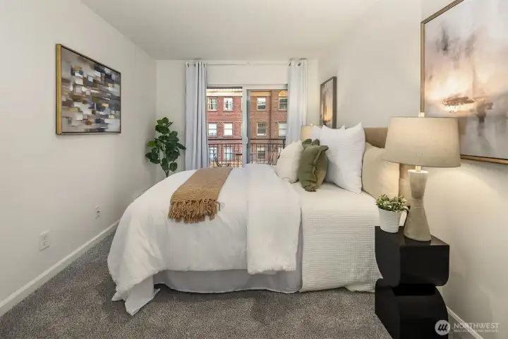 Primary bedroom has cool neutral tones and a slider door to a private balcony.