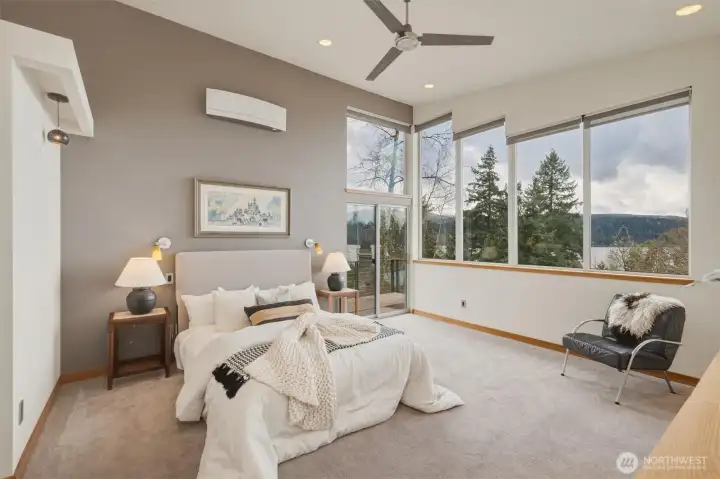 Second floor primary suite enjoys tremendous water views and natural light through an expansive wall of windows (blinds are controlled via wireless remotes).