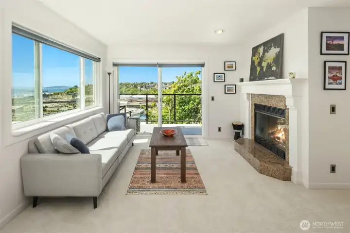 Bathed in light, the living area features access to the deck, a wood burning fireplace, and amazing views!
