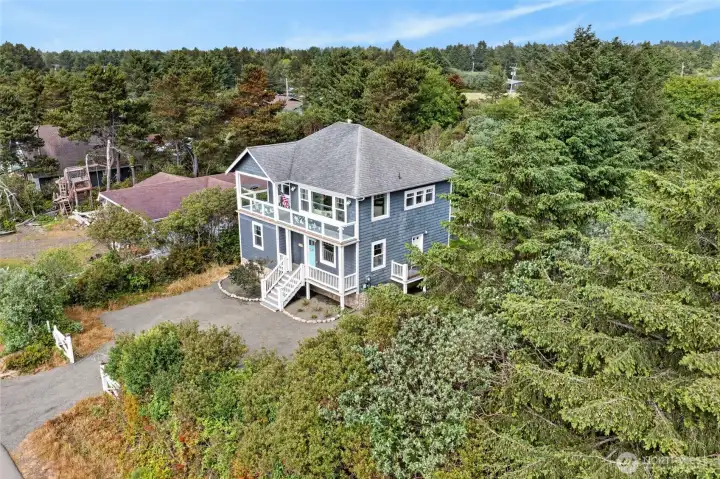 Bird's-eye view of 126 Sand Dune Ave NW! See the beautiful surrounding greenery, coastal neighborhood layout, and proximity to the Ocean Shores beaches.