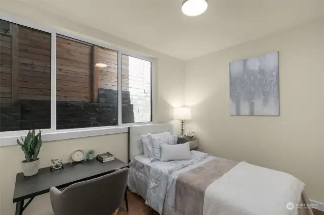 The guest suite showcases a wide paneled window and room to fit a bed and desk.
