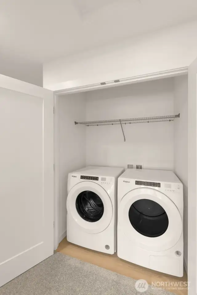 A dedicated laundry space with a modern Whirlpool washer and dryer, complemented by overhead shelving for effortless organization and convenience.
