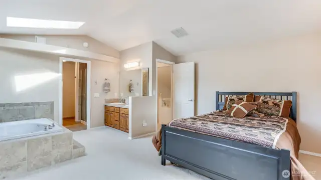 Upstairs primary bedroom features vaulted ceilings, new carpet and skylight.