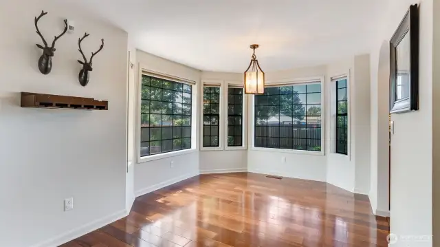 This stunning circular dining area is surrounded by tall windows, flooding the space with natural light and backyard views.