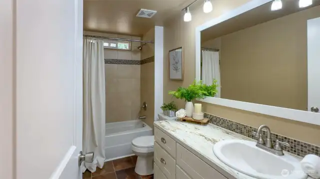 Guest bathroom with large vanity and tile shower.