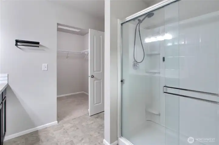 Primary suite ensuite 3/4 bath view showing shower and walk-in closet.
