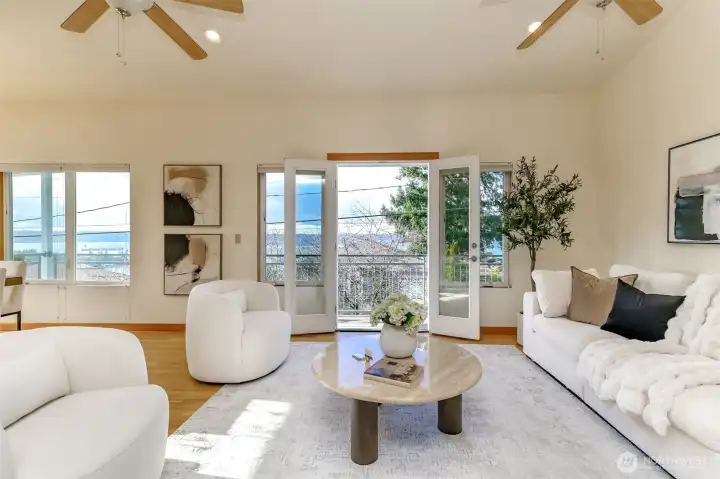 Living room with White oak hardwood floors, skylights and ceiling fans and doors out to deck.