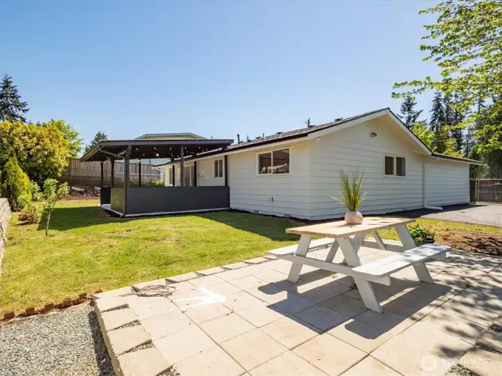 Paved area and lawn offering space for outdoor dining and play. Image from earlier listing in Sep 2025.