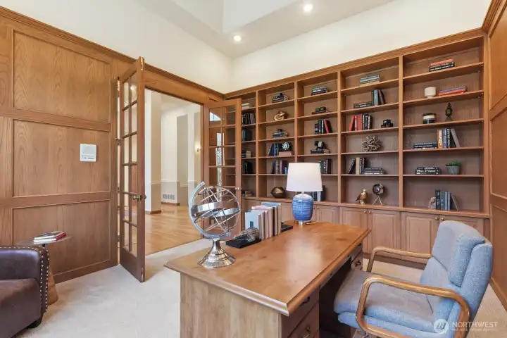 The generously sized study is located off the foyer through French doors and boasts fully paneled walls, tall ceiling height with crown molding, brand new textured carpet and a wall of built-in bookcases and cabinets.