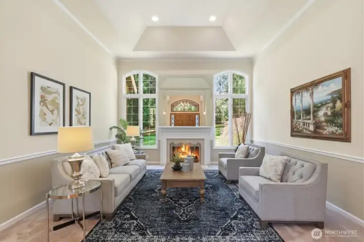 Formal living room with tall coved ceiling with crown molding, wainscoting and marble surround masonry fireplace.