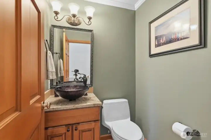 The guest ½ bath with floating vessel sink is off the foyer hallway.