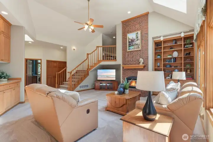 The informal gathering room with a tall vaulted ceiling with skylights a look to ceiling neck fireplace.