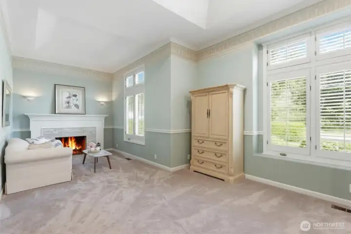 Sitting area with stone surround masonry wood burning fireplace and sconce lighting.